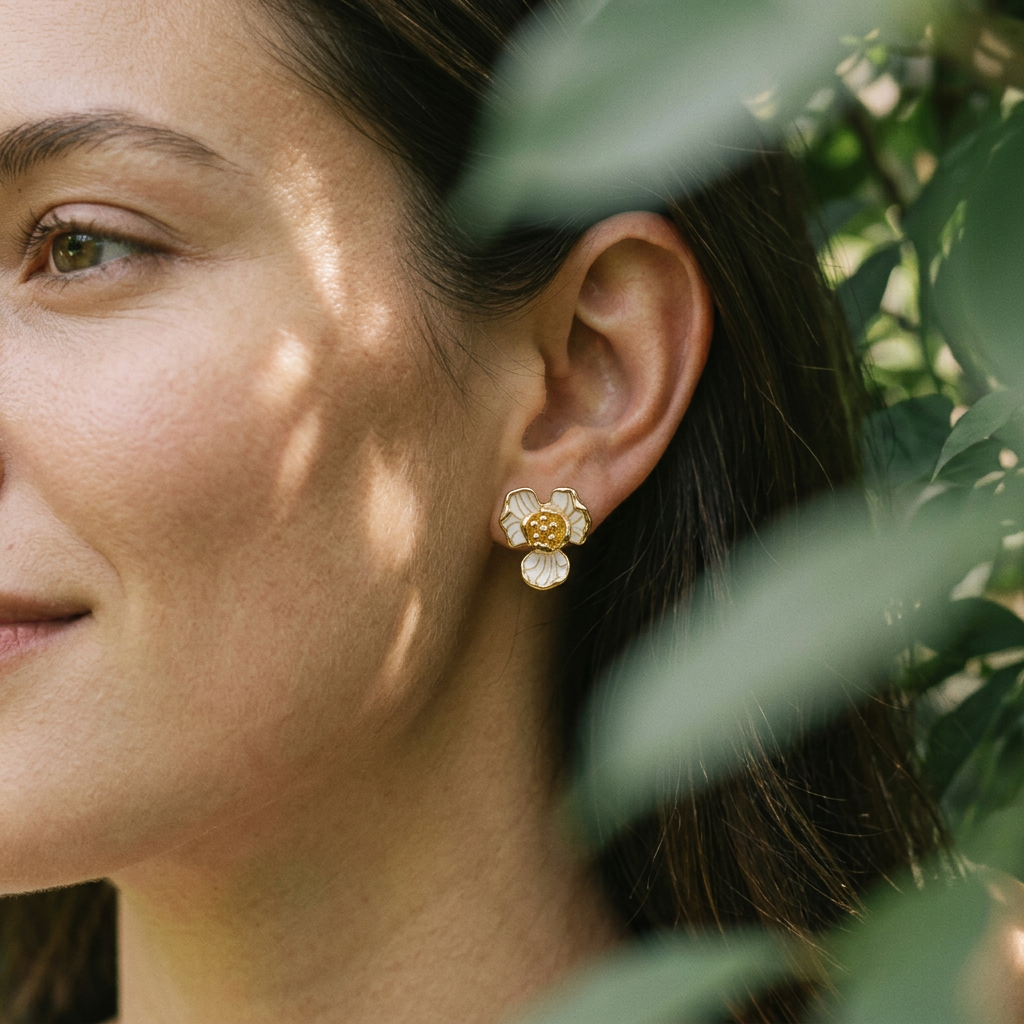 Close-up of a woman wearing floral earrings with green leaves in the background