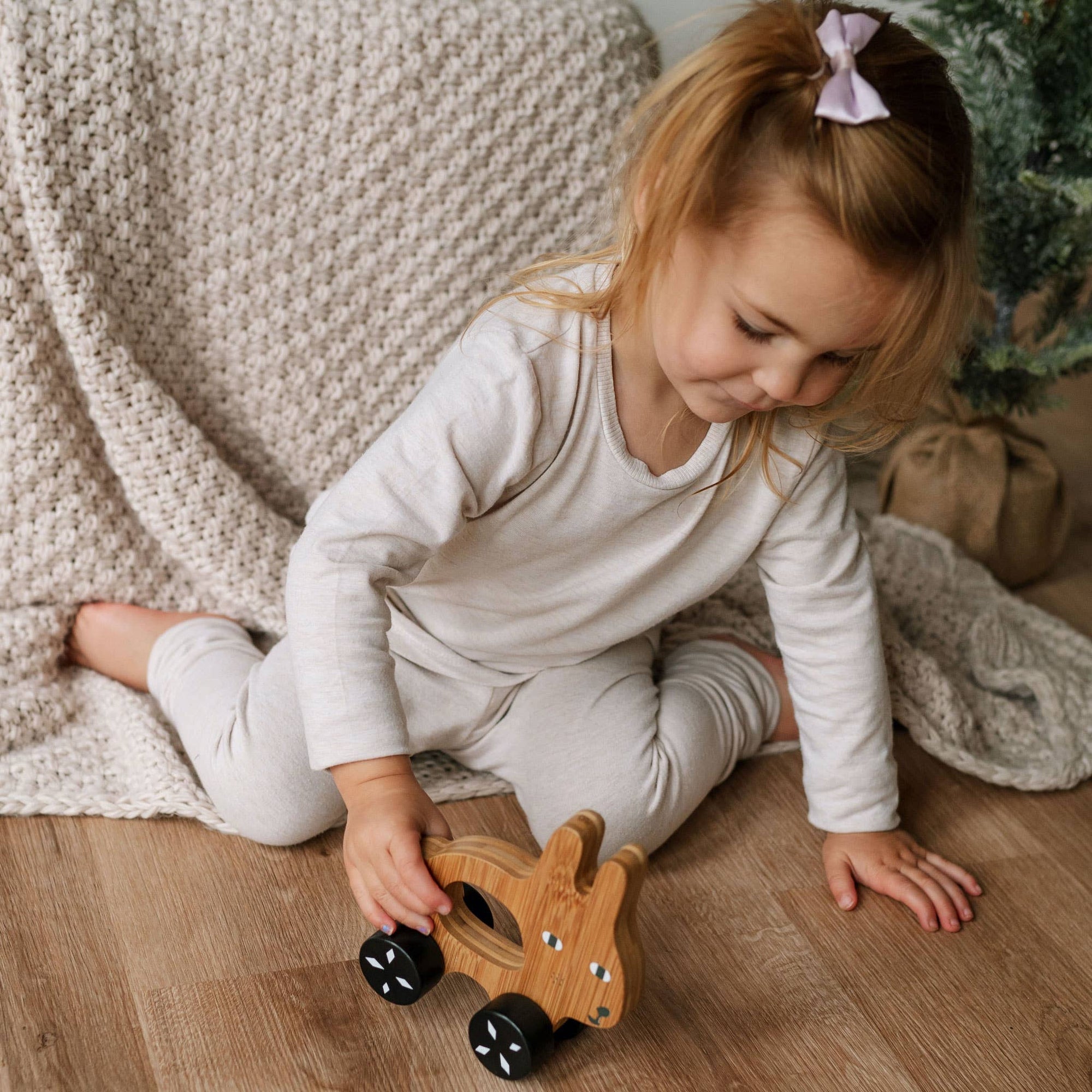 Child playing with a wooden toy on a wooden floor.