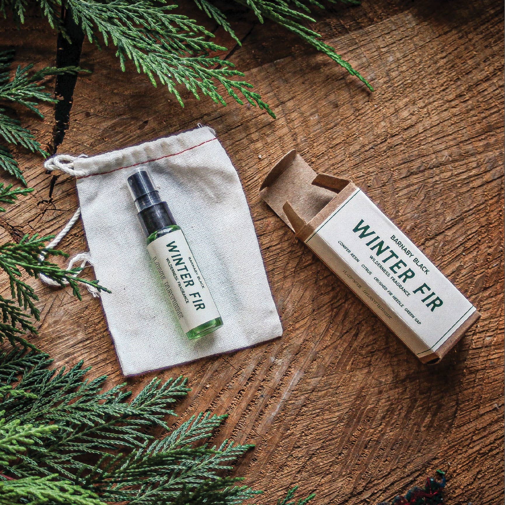 Winter Fir product with packaging on a wooden surface surrounded by greenery