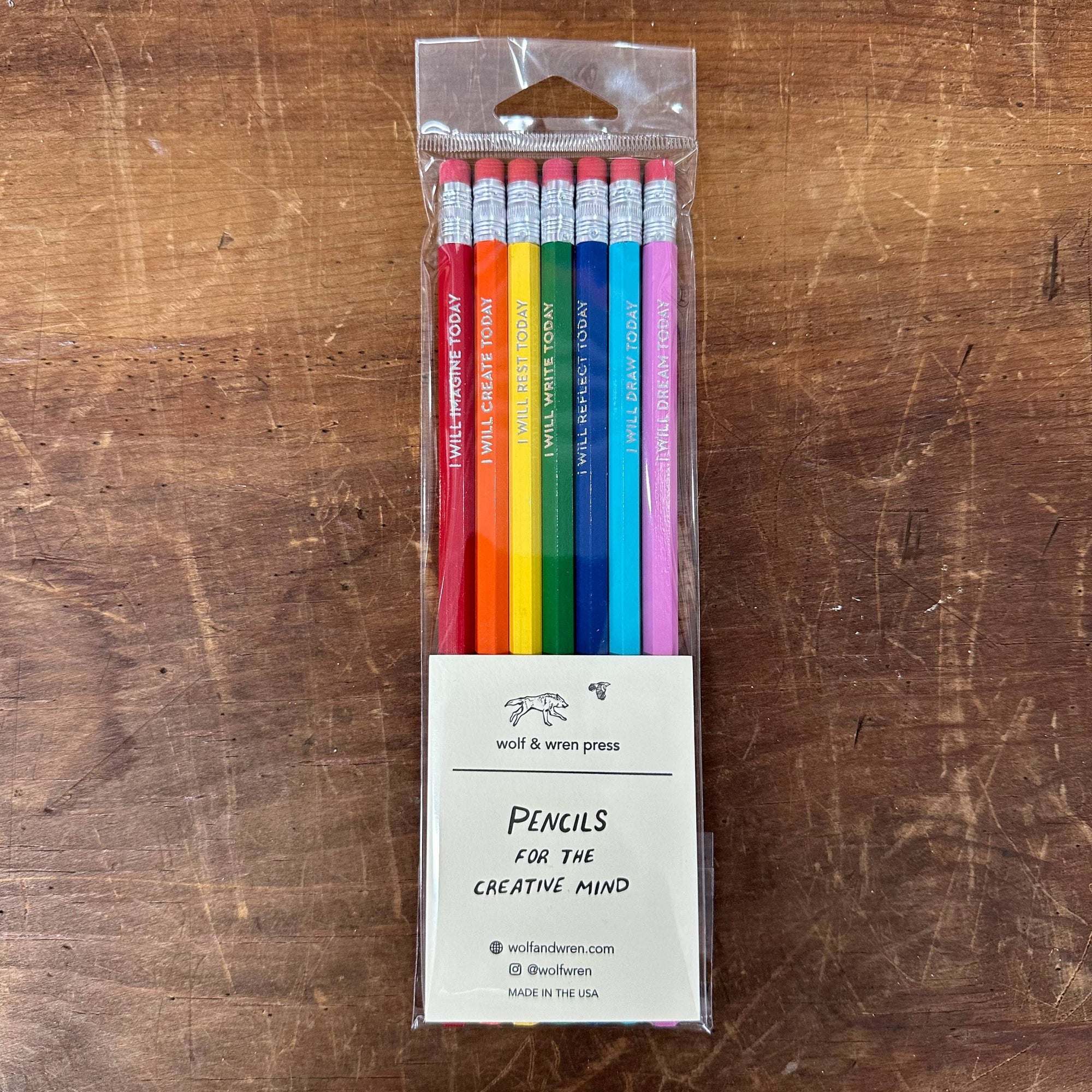 Packaged set of colorful pencils with a label on a wooden surface