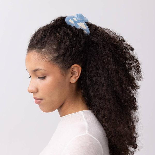Woman with curly hair wearing a blue hair accessory against a white background