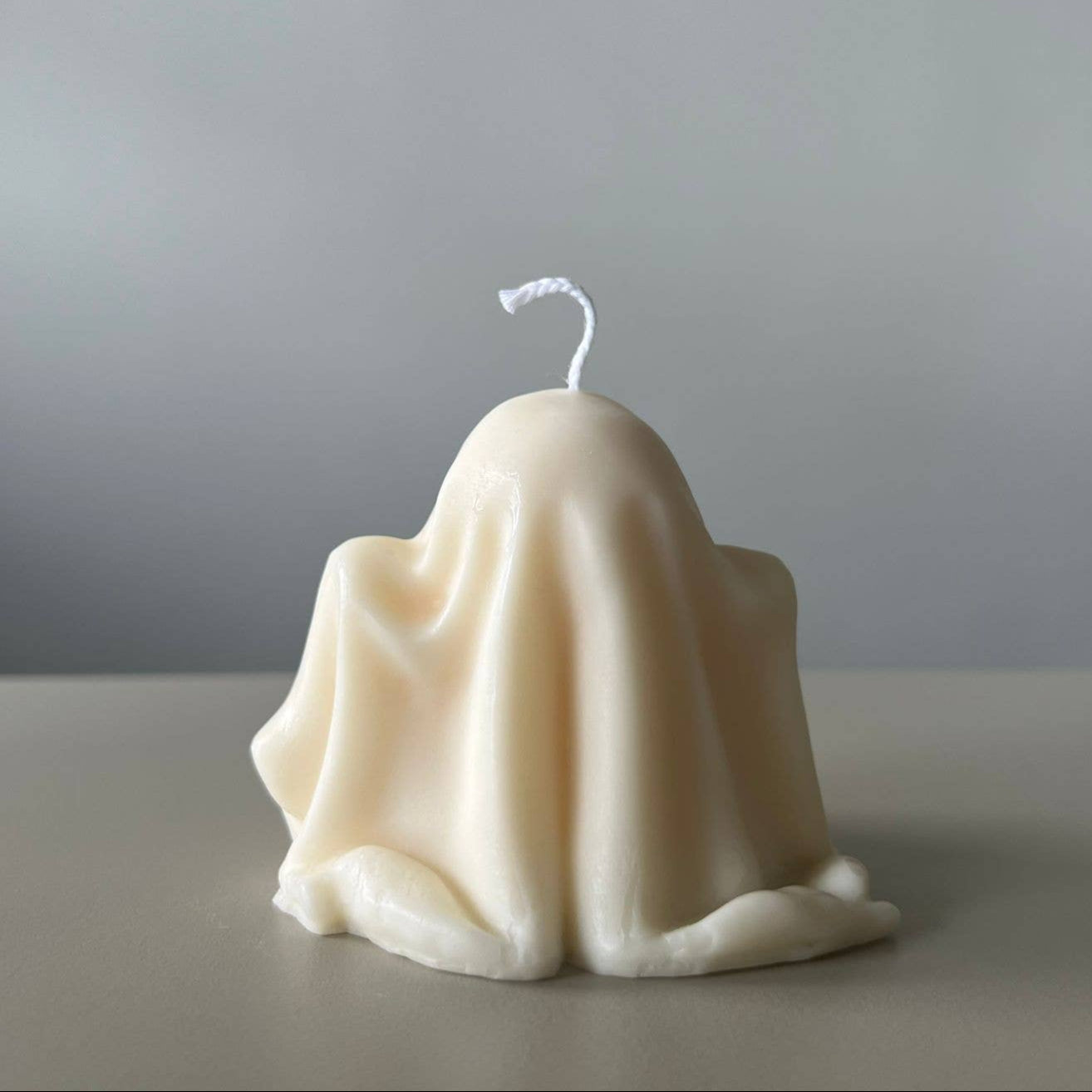 Ghost-shaped candle on a plain background