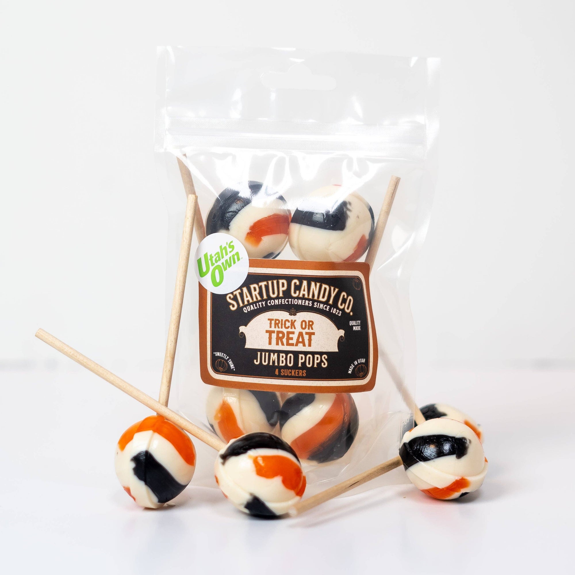A bag of black, white and orange lollipops with a tag that reads "Startup Candy Co. Trick or Treats Jumbo Pops" against a white background