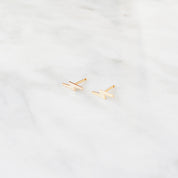 Gold lightning bolt shaped earrings on a light gray background