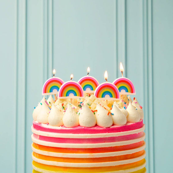 Colorful birthday cake with rainbow candles and pink background