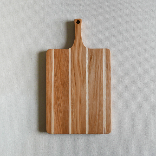 Wooden cutting board with a handle on a light gray background