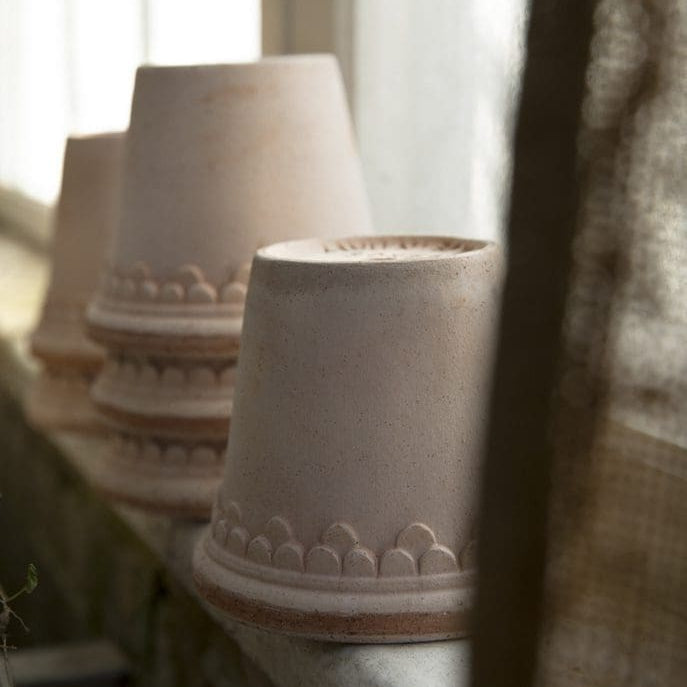 Row of ceramic pots with decorative patterns on a surface near a window.