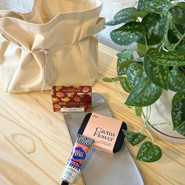 Cosmetic items including a tube of cream, a box of incense, and a plant on a wooden surface.