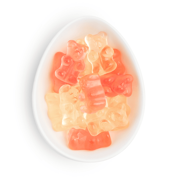 Gummy bears in pink and orange on a white plate with a white background