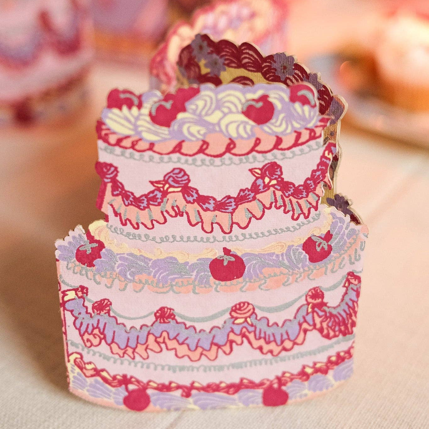 Decorative paper cake with pink and purple details on a neutral background