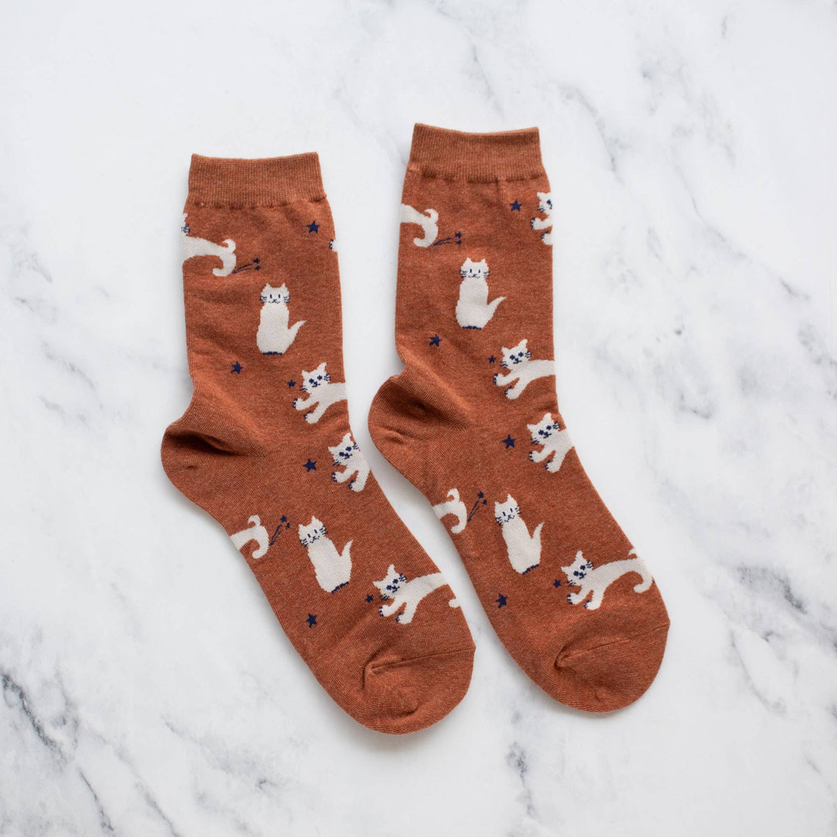 Pair of brown socks with cat pattern on a marble surface