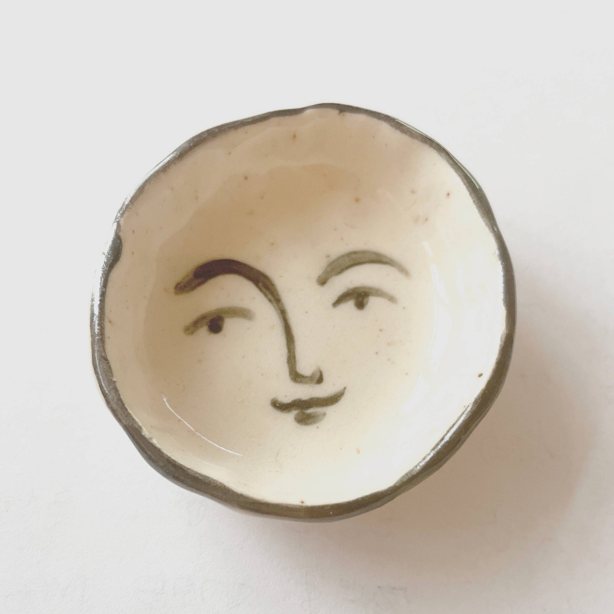 Ceramic dish with a face design on a white background
