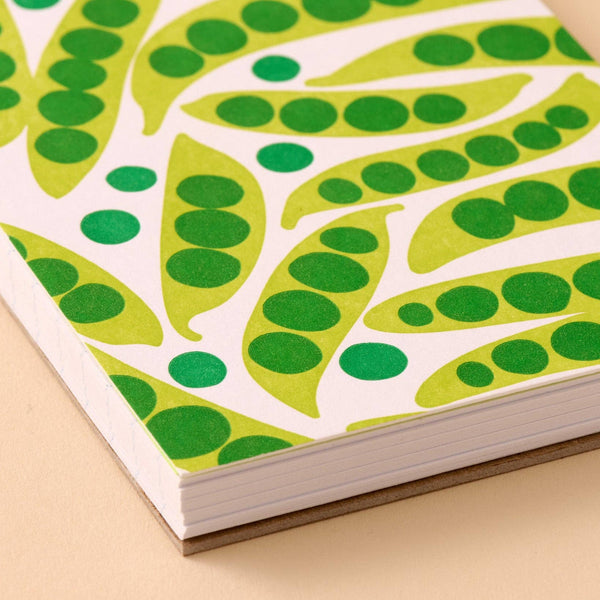 Notebook with green pea pod pattern on a beige background