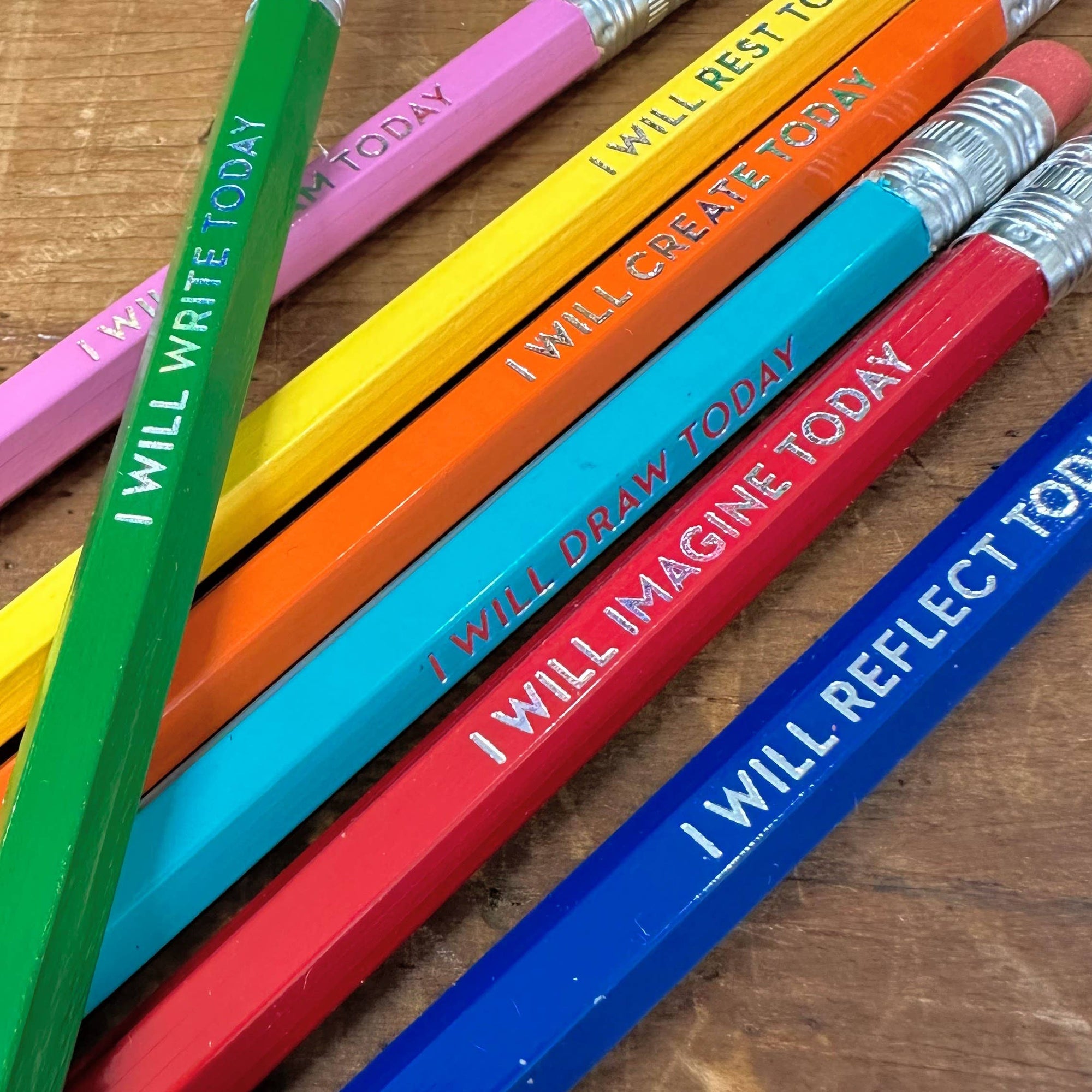 Colorful pencils with motivational phrases on a wooden surface