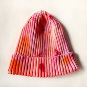 Knitted beanie with a gradient of pink, orange, and red on a light background