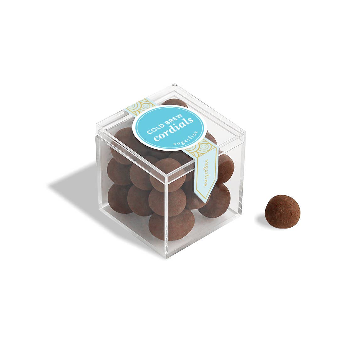Clear cube box with brown spherical candies and a blue label on a white background