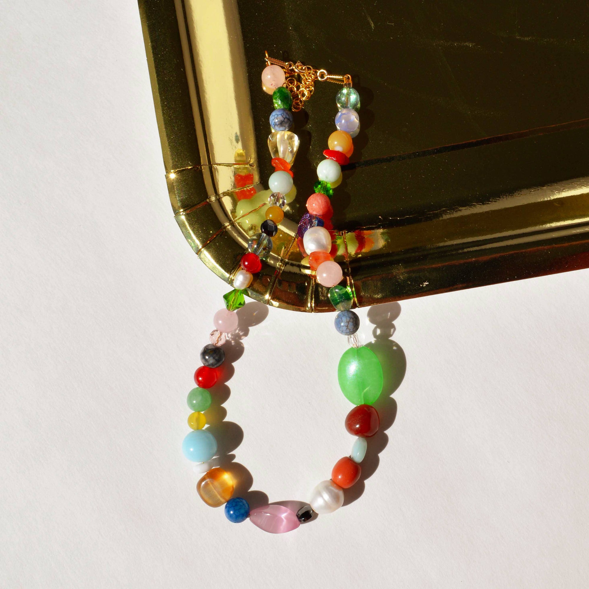 Colorful beaded earring on a gold mirror background