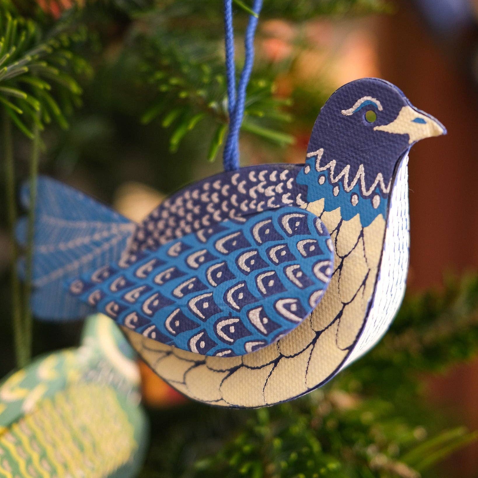blue dove ornament hanging on a fir-like Christmas tree branch