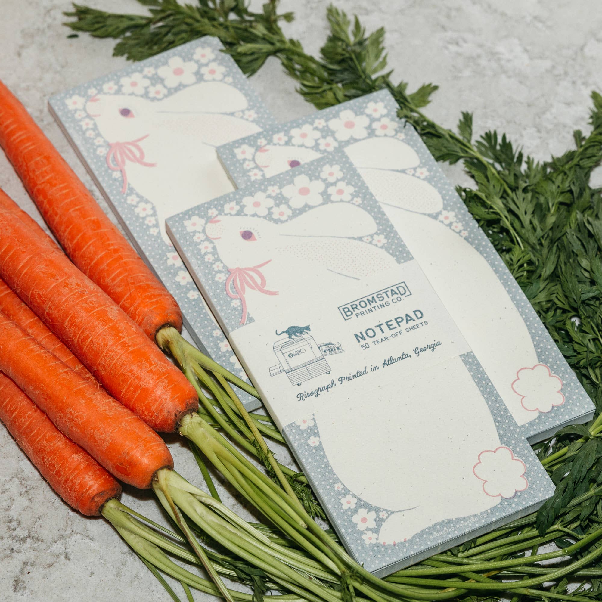 Notepad with rabbit design laying on a bed of carrots and greenery