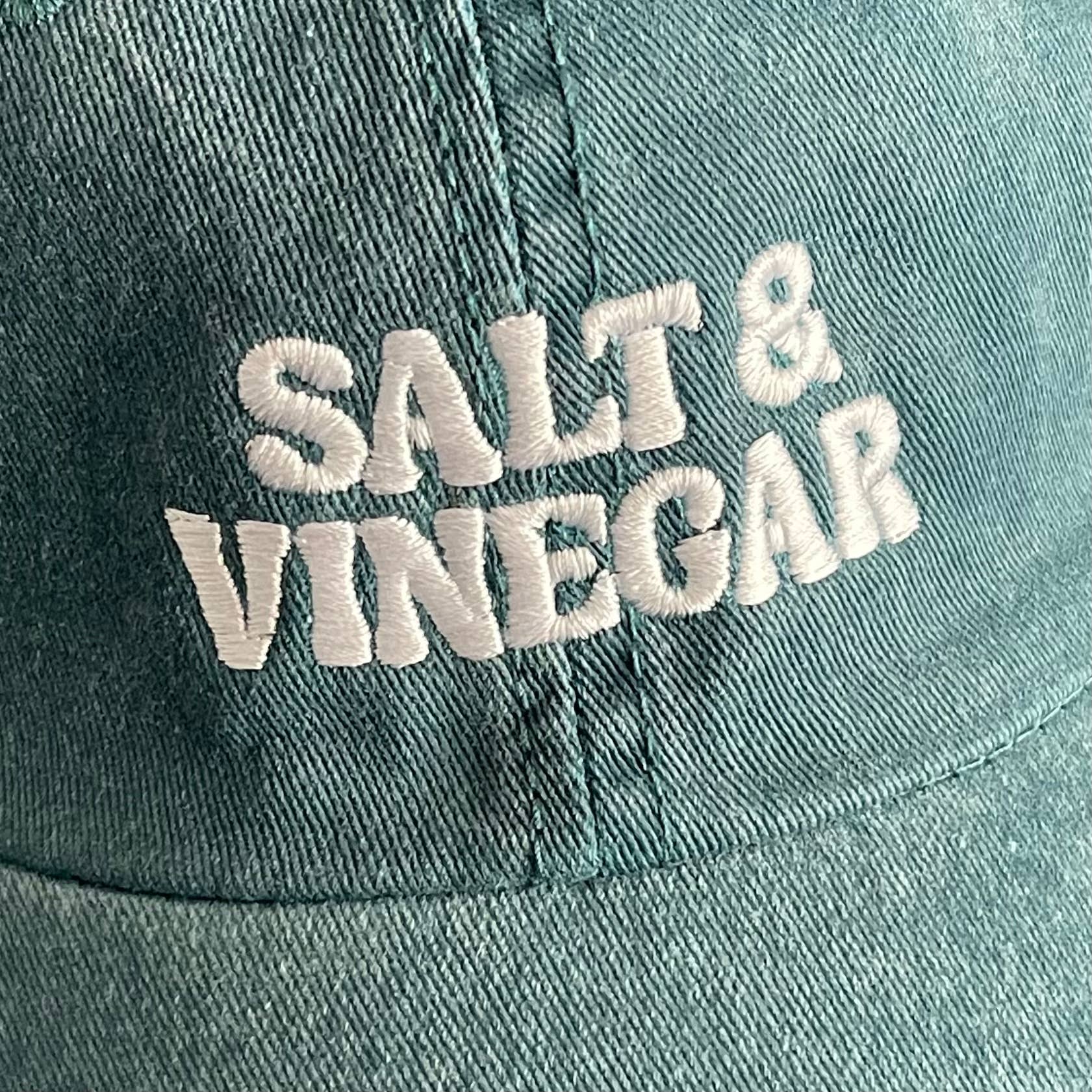 Teal cap with 'Salt & Vinegar' embroidered in white on a close-up view.
