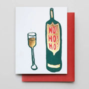 A square greeting card with a white front showing a hand-drawn green bottle and glass with red 'HO! HO! HO!' lettering, placed over a red envelope on a light gray background.