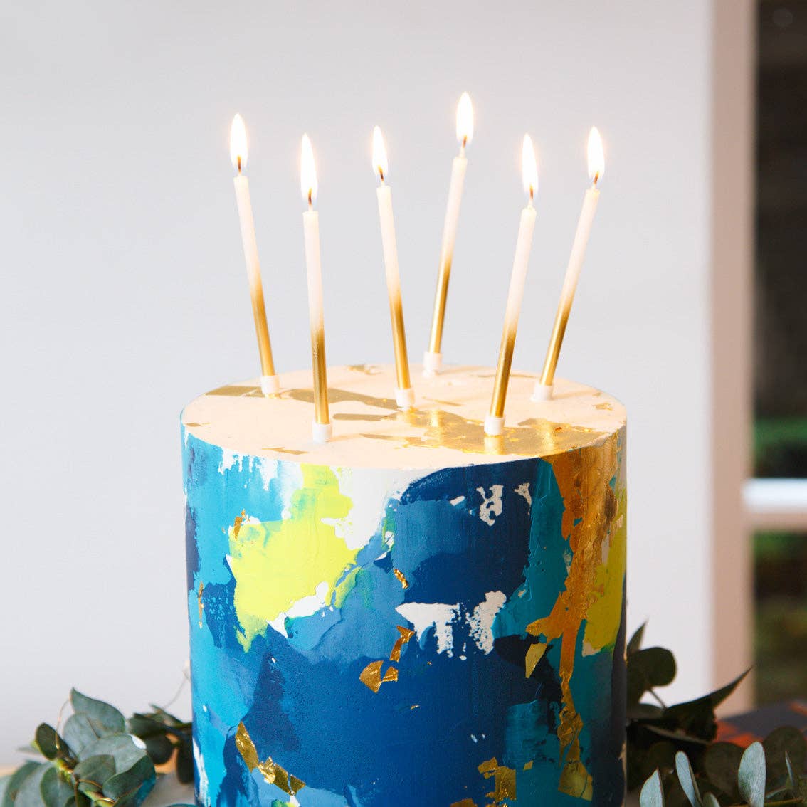 Colorful candle with lit candles on a white background