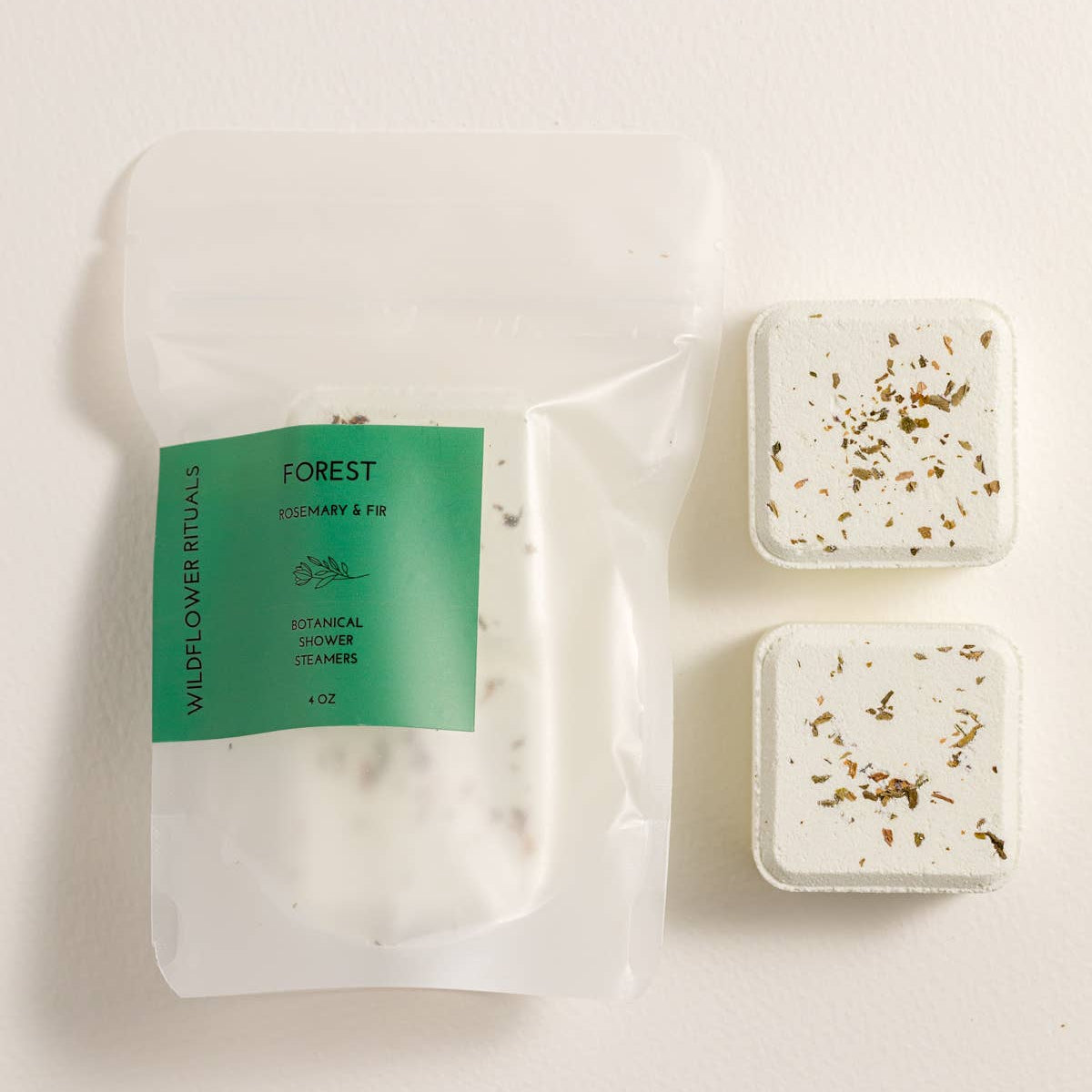 Two square botanical shower steamers with a visible label on a white background