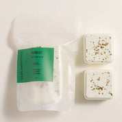 Two square botanical shower steamers with a visible label on a white background
