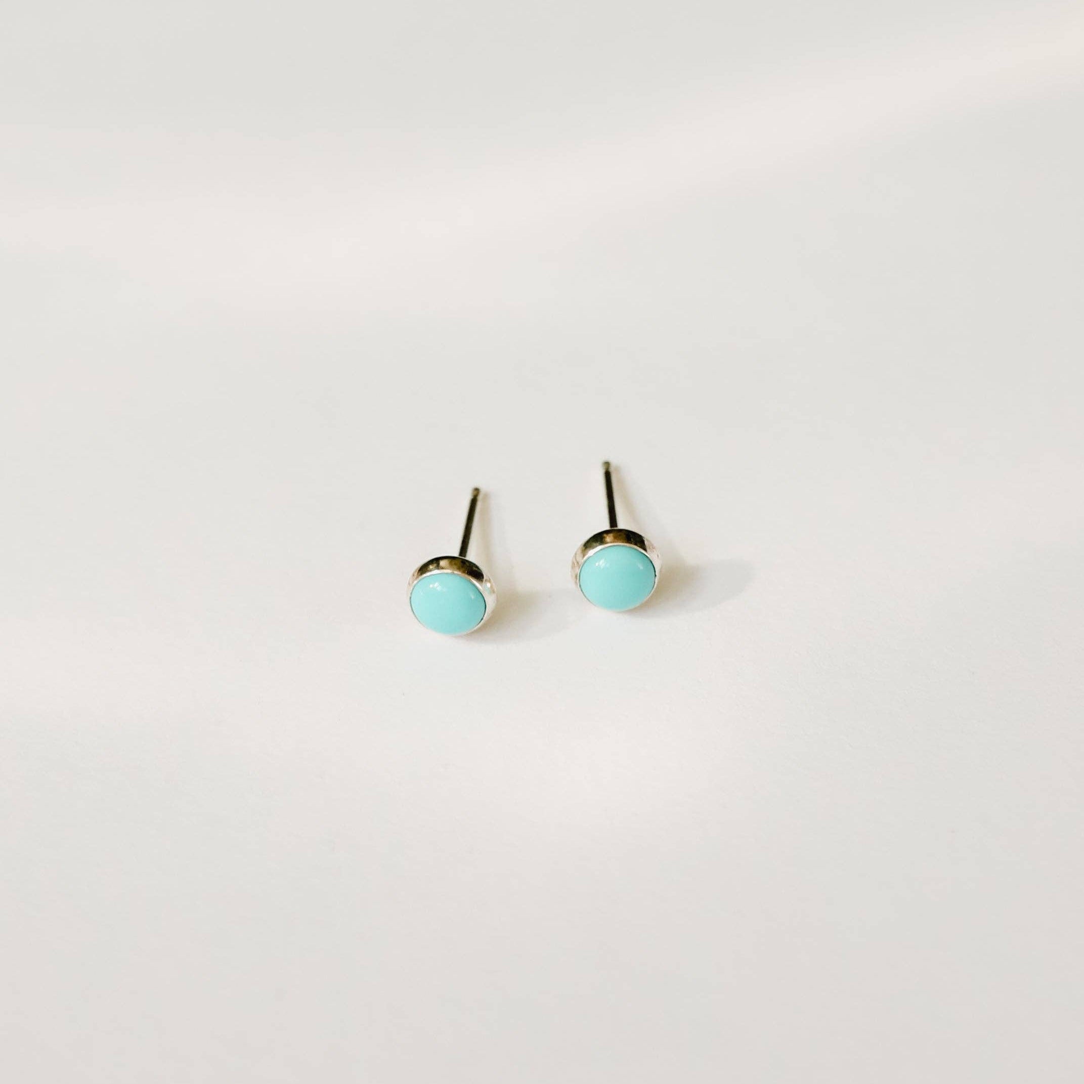 Pair of turquoise stud earrings on a white background