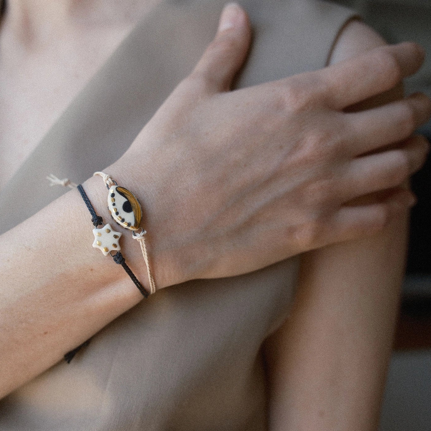 Close-up of a person's wrist wearing multiple bracelets with a neutral background
