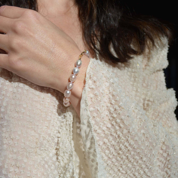 Pearl bracelet on a wrist with a textured beige garment