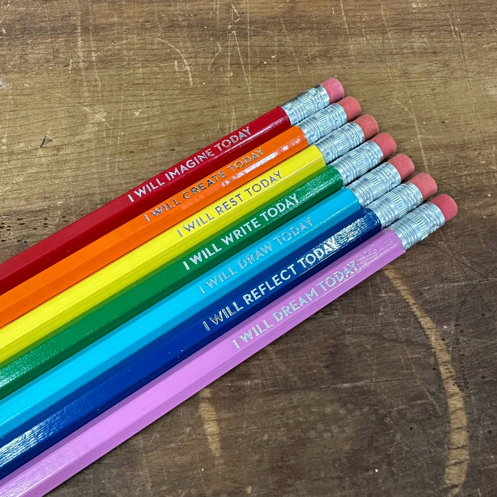 Set of colorful pencils with motivational phrases on a wooden surface