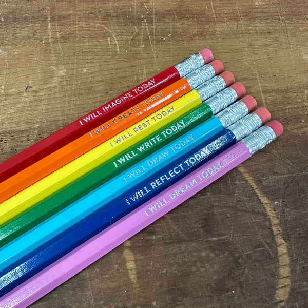 Set of colorful pencils with motivational phrases on a wooden surface