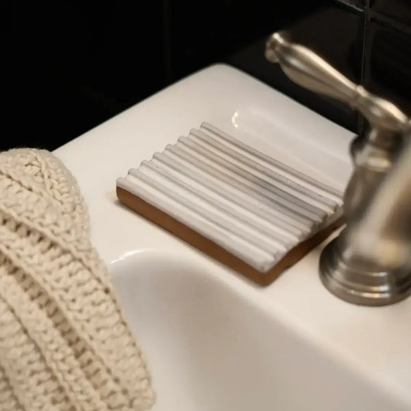 Soap dish with soap on a sink next to a towel