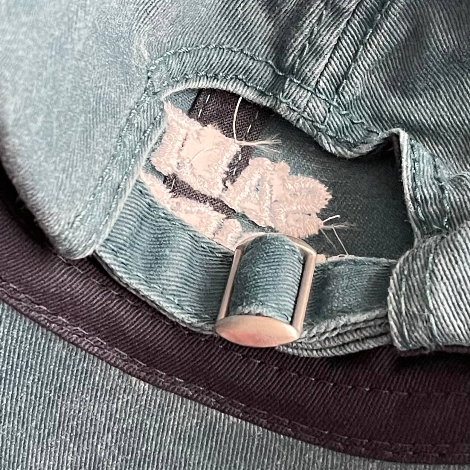 Close-up of a green cap with a strap and buckle detail.