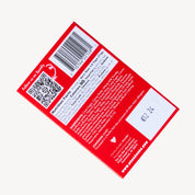 The back of a red packaged food product, shown on a light gray background. The package includes a barcode, QR code, nutrition facts, ingredients list, and a handwritten price sticker.