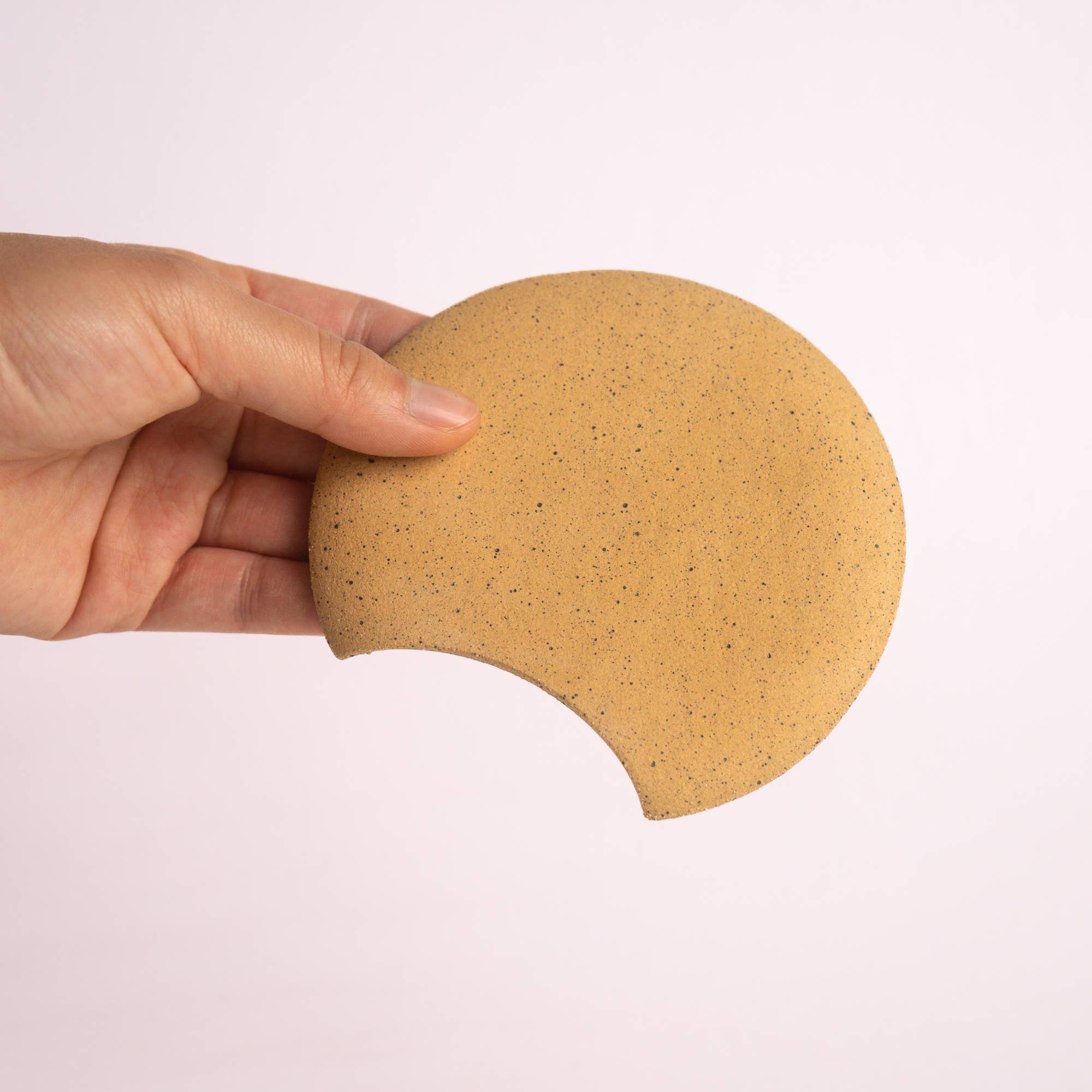 A hand holding a spoon rest with the back facing the camera