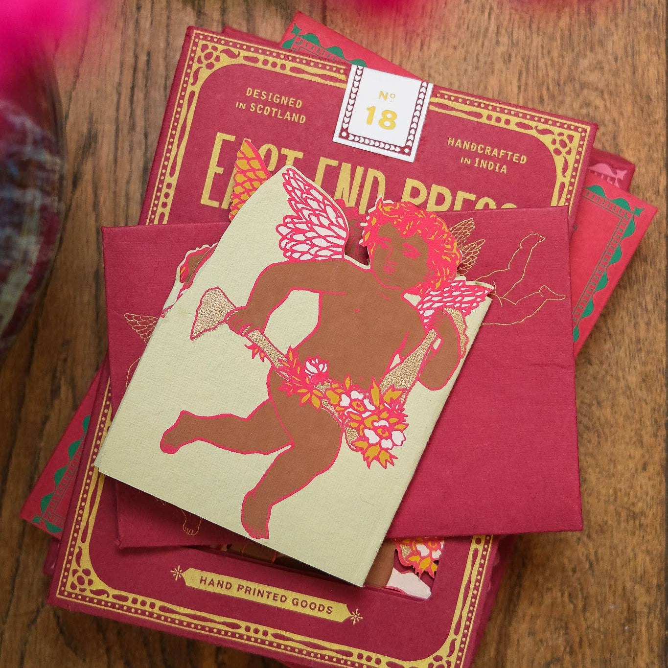 Stack of cupid greeting cards with a decorative design on a wooden surface
