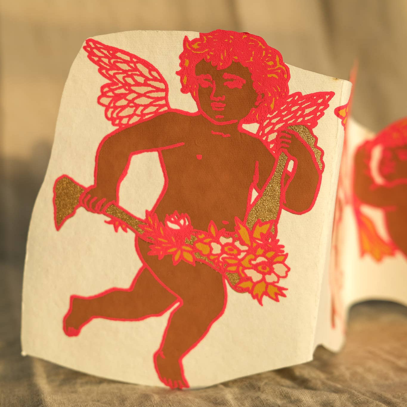 Red cherub illustration on a white card with a blurred background