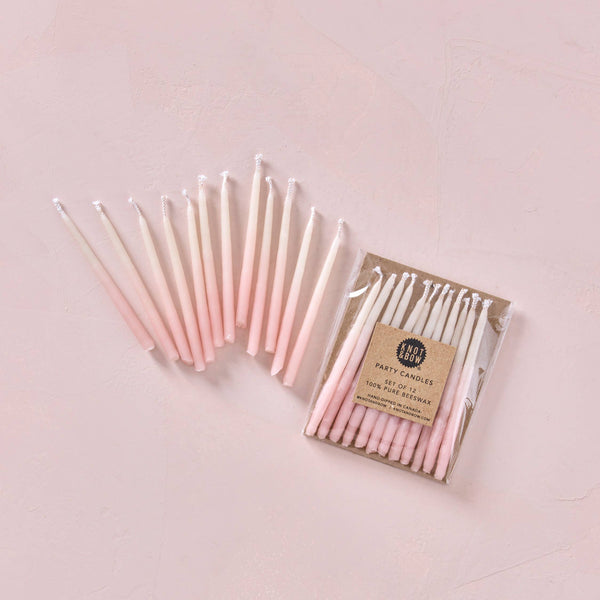 Pack of pink candles with a visible brand label on a light pink background
