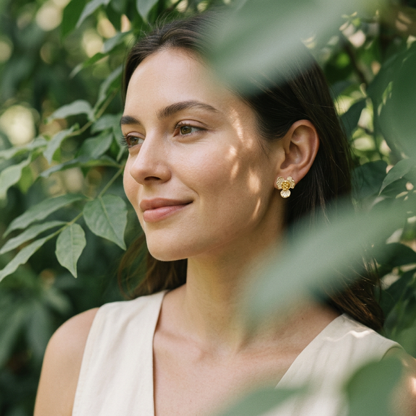 Woman with earrings standing among green leaves