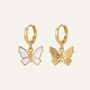 Gold butterfly earrings on a light beige background