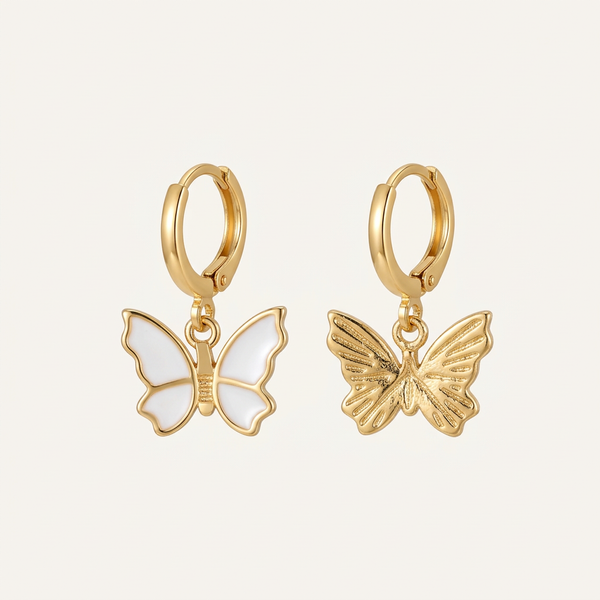 Gold butterfly earrings on a light beige background