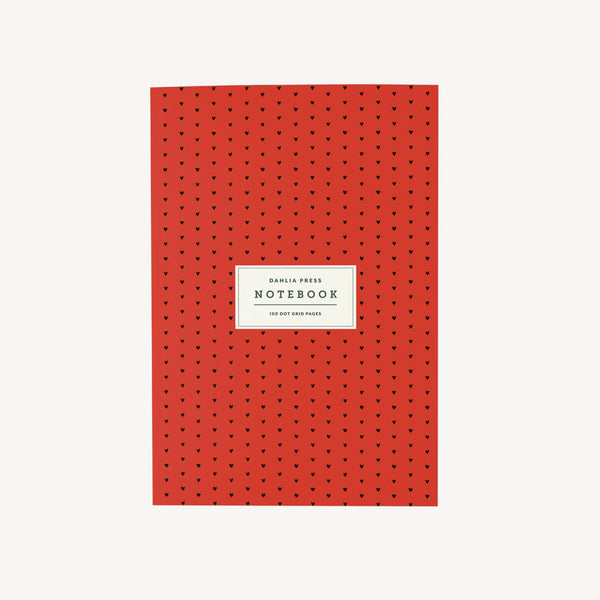 Red notebook with small black heart pattern and a white label on a light gray background