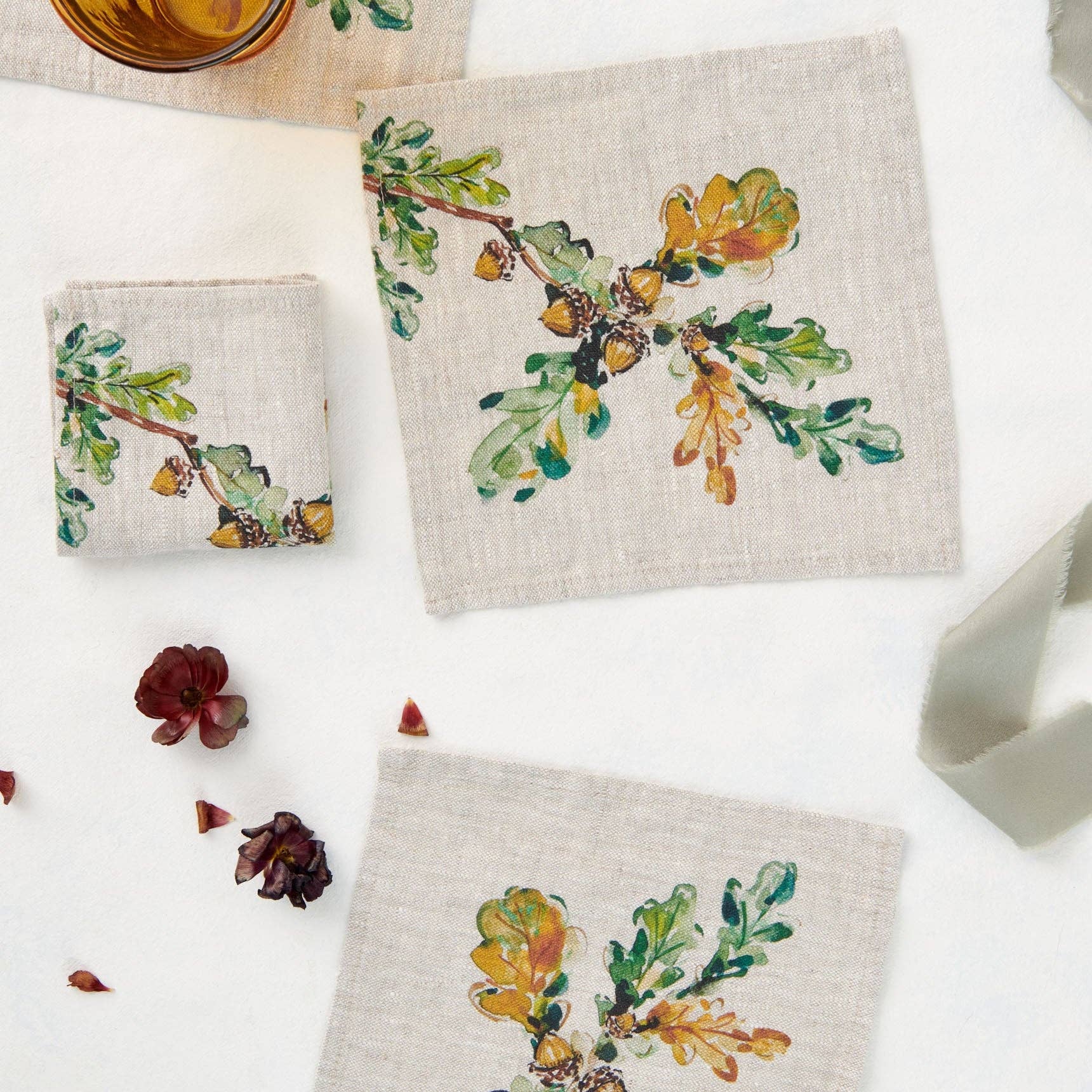Set of three linen coasters with autumn-themed designs on a white surface.