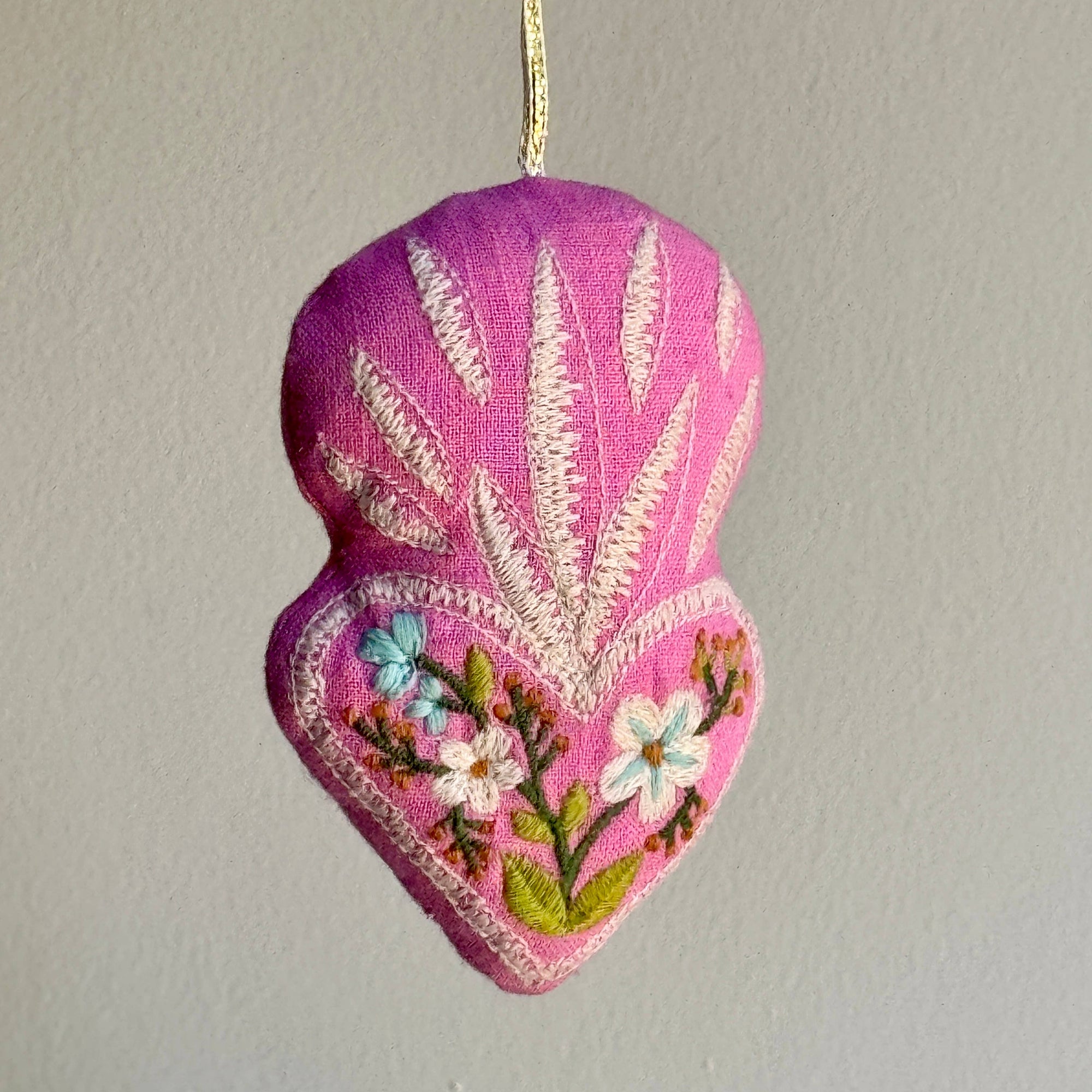 Embroidered heart-shaped ornament with floral designs on a plain background