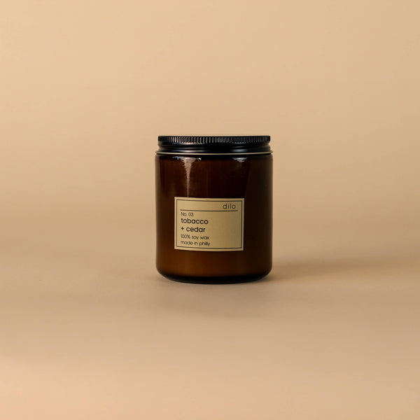 Brown candle jar with black lid on a beige background