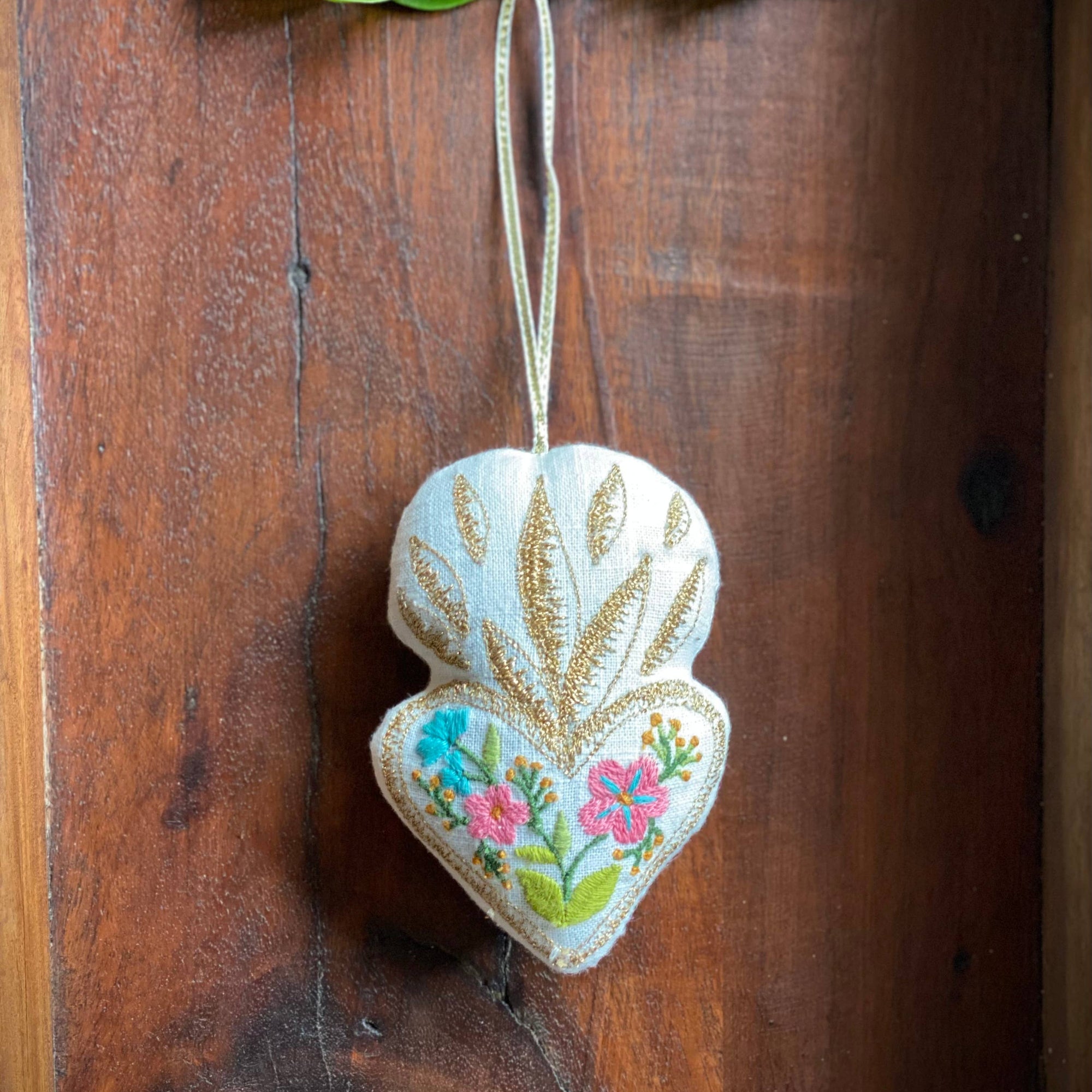 Decorative heart-shaped ornament with floral patterns hanging on a wooden door.