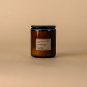 An amber glass jar candle with a black metal lid and a minimalist white label reading 'd10 sandalwood', set against a solid beige background.