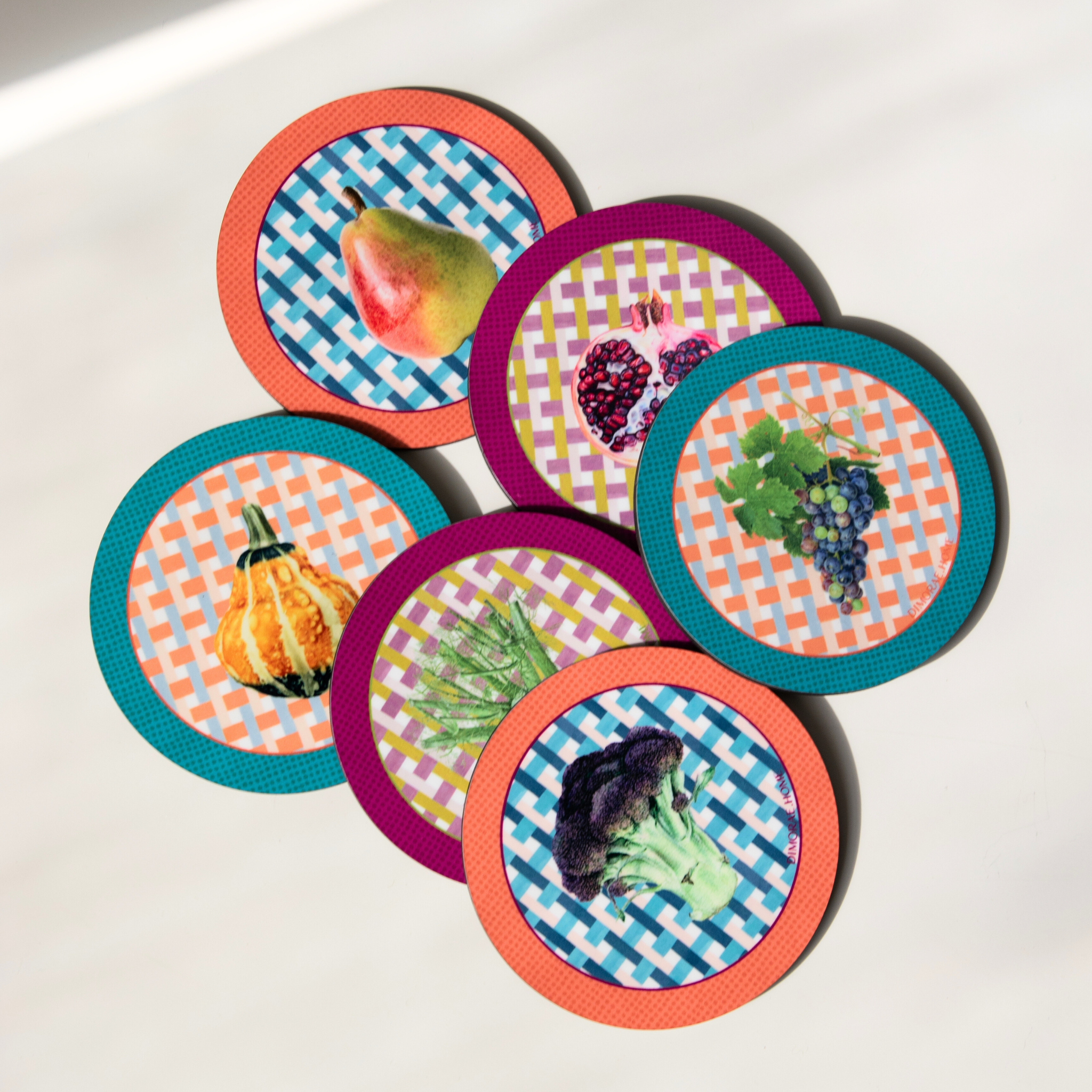 Dimorae Crisp Coaster Set featuring four stylish coasters with a modern design on a wooden table background.